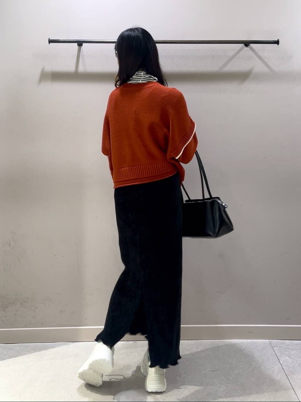レッド系のニット/セーター、ブラック系のスカート、ホワイト系のスニーカーを着用したレディースの冬コーディネートの3枚目の写真