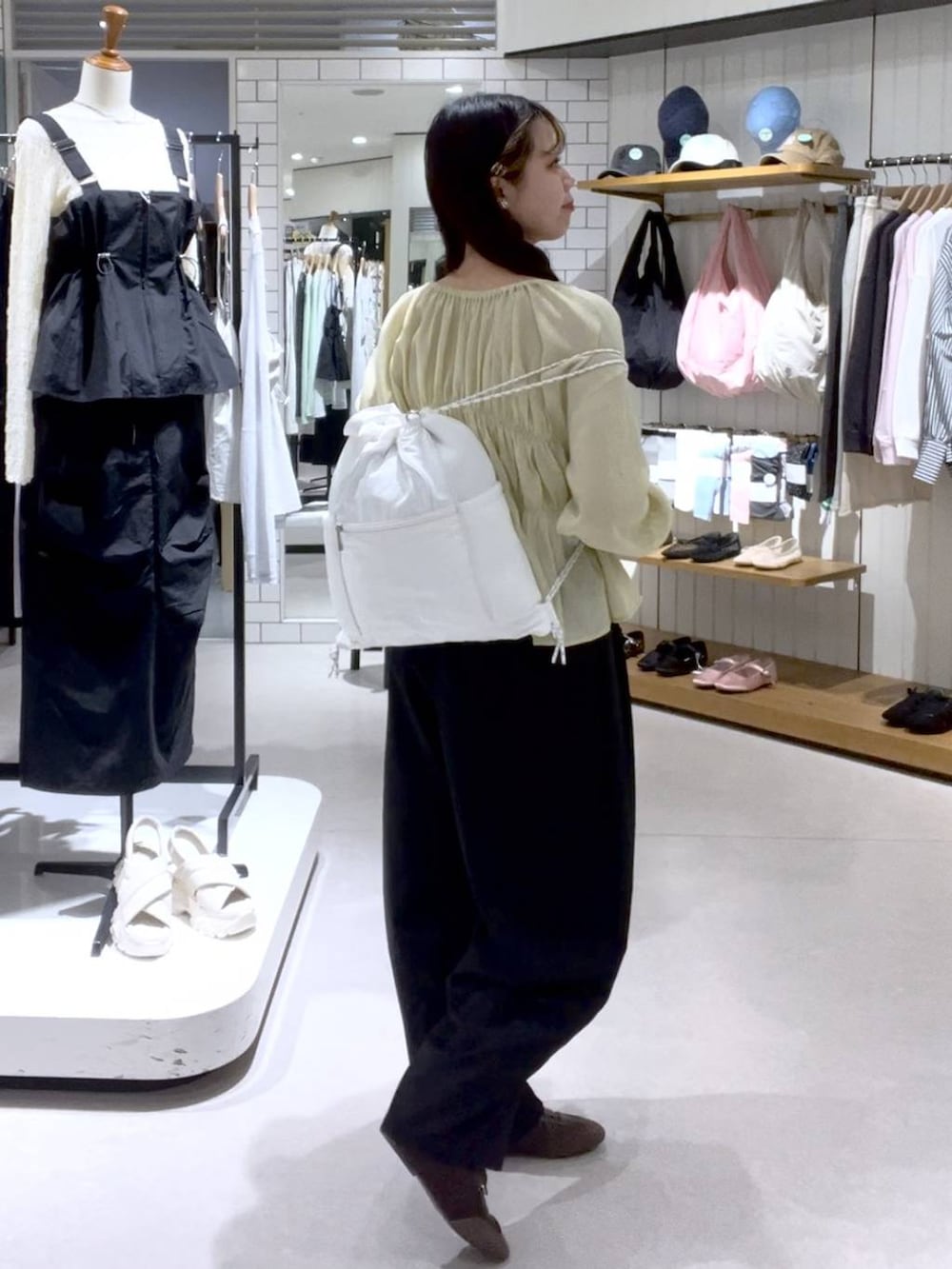 ブラウン系のスニーカー、ベージュ系のキャミソール、ホワイト系のバックパック/リュックを着用したレディースの春コーディネートの4枚目の写真