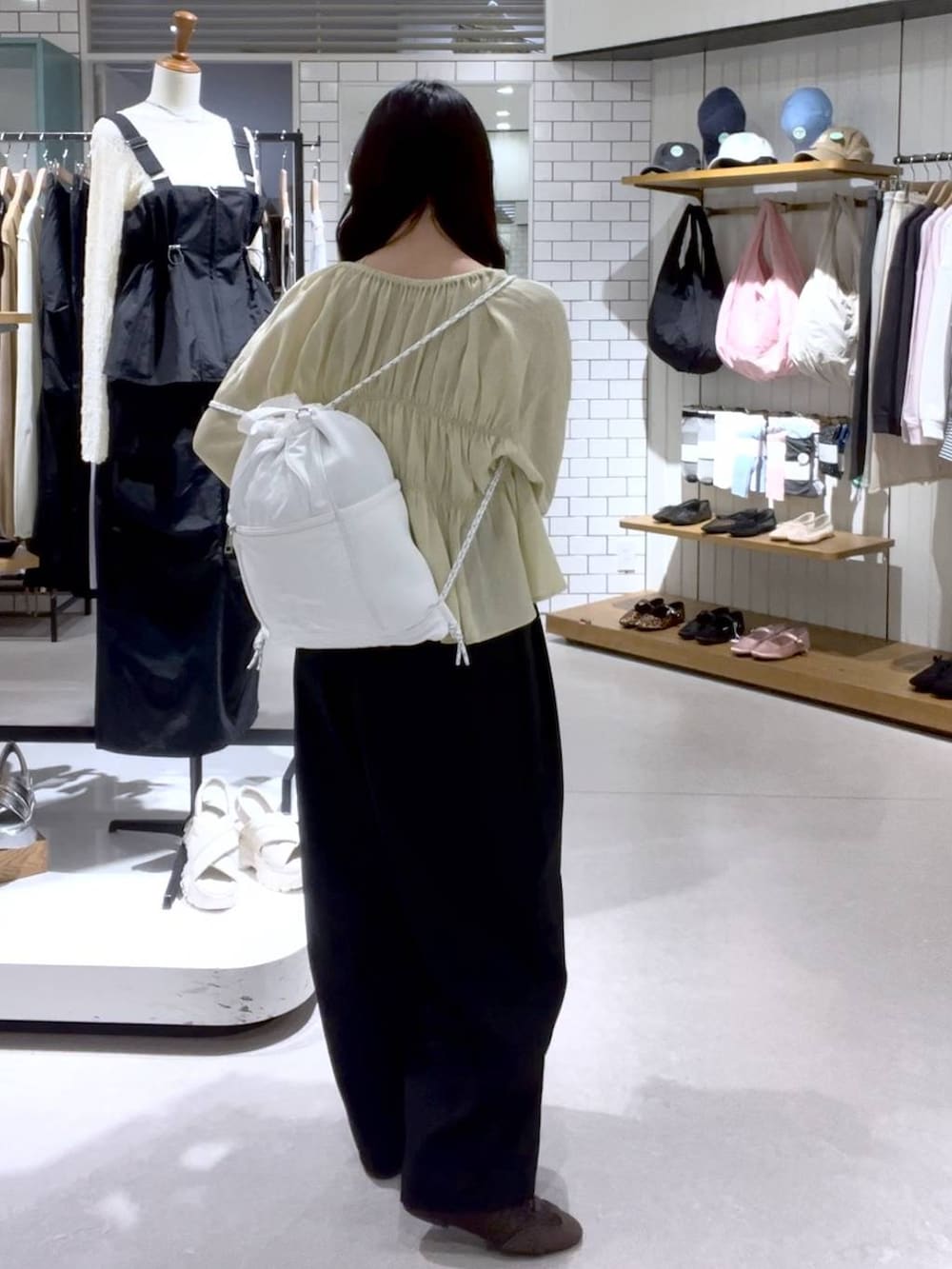 ブラウン系のスニーカー、ベージュ系のキャミソール、ホワイト系のバックパック/リュックを着用したレディースの春コーディネートの3枚目の写真