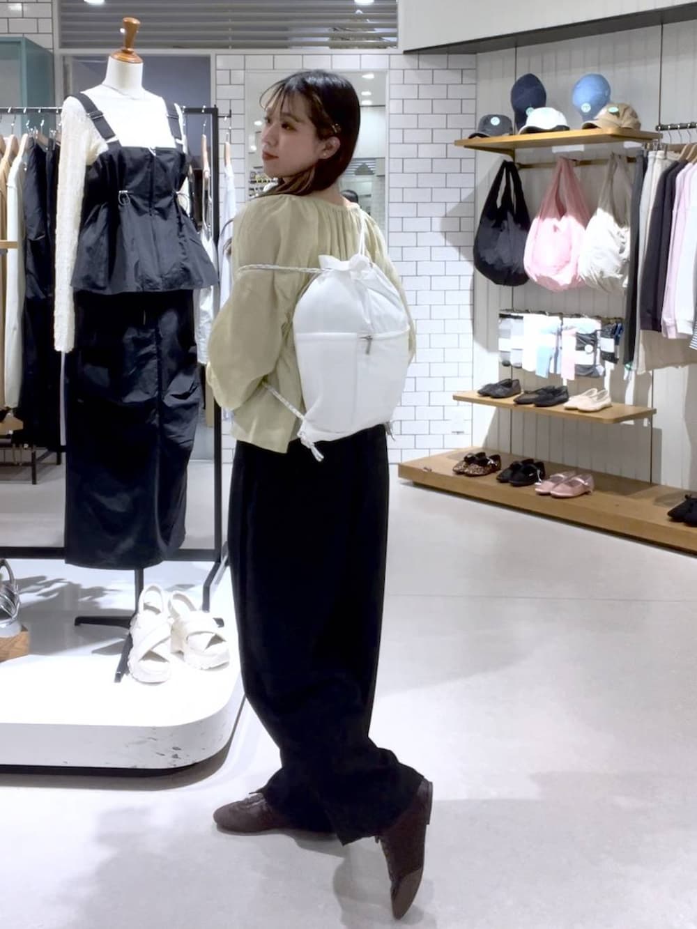 ブラウン系のスニーカー、ベージュ系のキャミソール、ホワイト系のバックパック/リュックを着用したレディースの春コーディネートの2枚目の写真