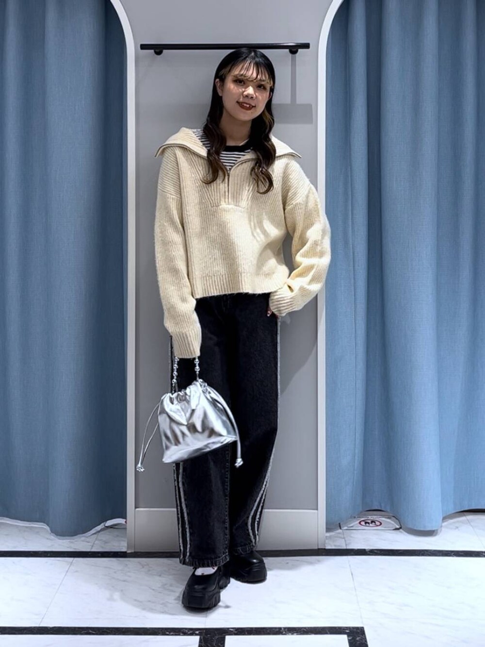 ブラック系のニット/セーター、シルバー系のショルダーバッグ、ブラック系のデニムパンツを着用したレディースの秋コーディネートの7枚目の写真