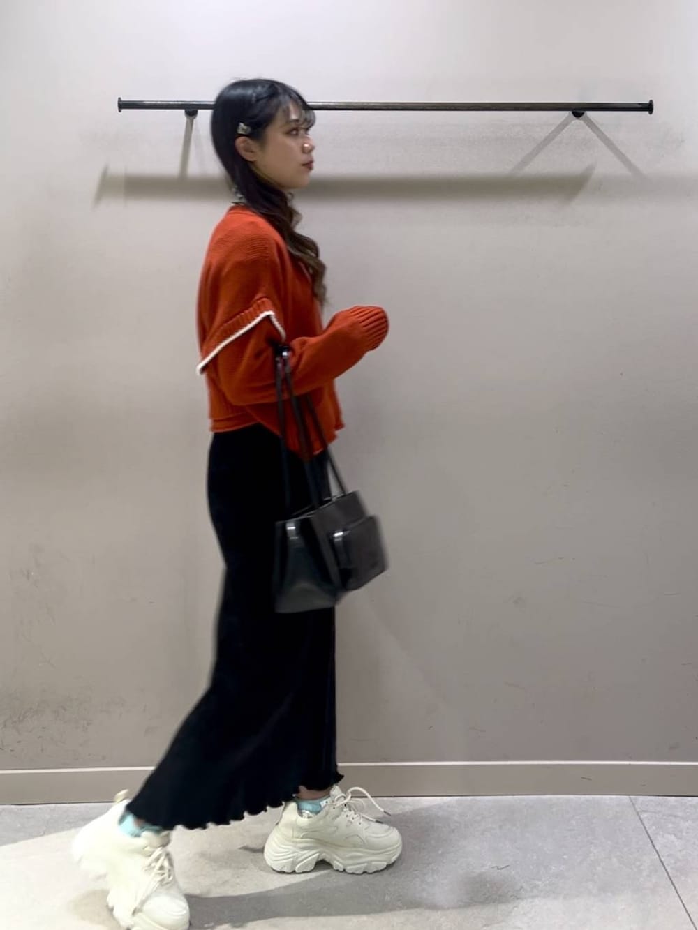 レッド系のニット/セーター、ブラック系のスカート、ホワイト系のスニーカーを着用したレディースの冬コーディネートの4枚目の写真