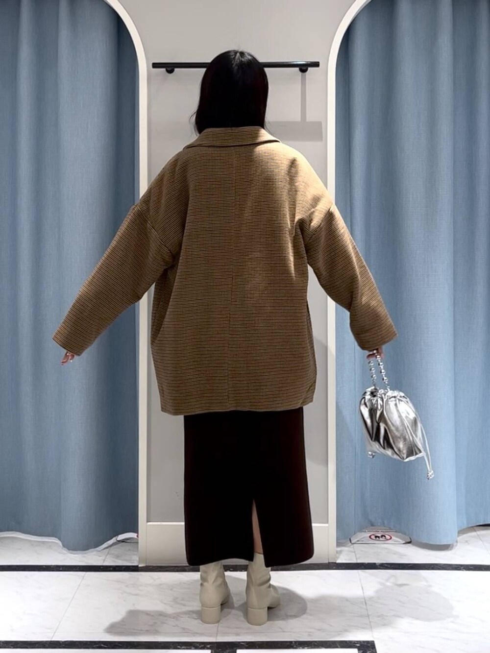 シルバー系のショルダーバッグ、ホワイト系のブーツ、その他のテーラードジャケットを着用したレディースの冬コーディネートの8枚目の写真