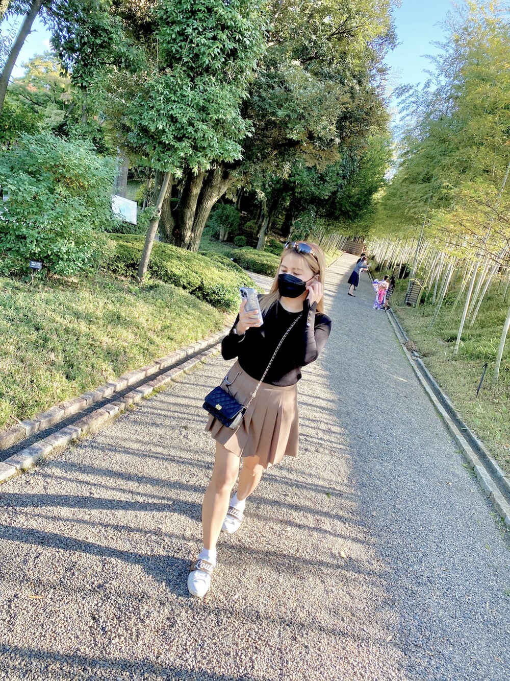 ホワイト系のスニーカー、ブラック系のニット/セーター、ベージュ系のスカートを着用したレディースの夏コーディネートの3枚目の写真