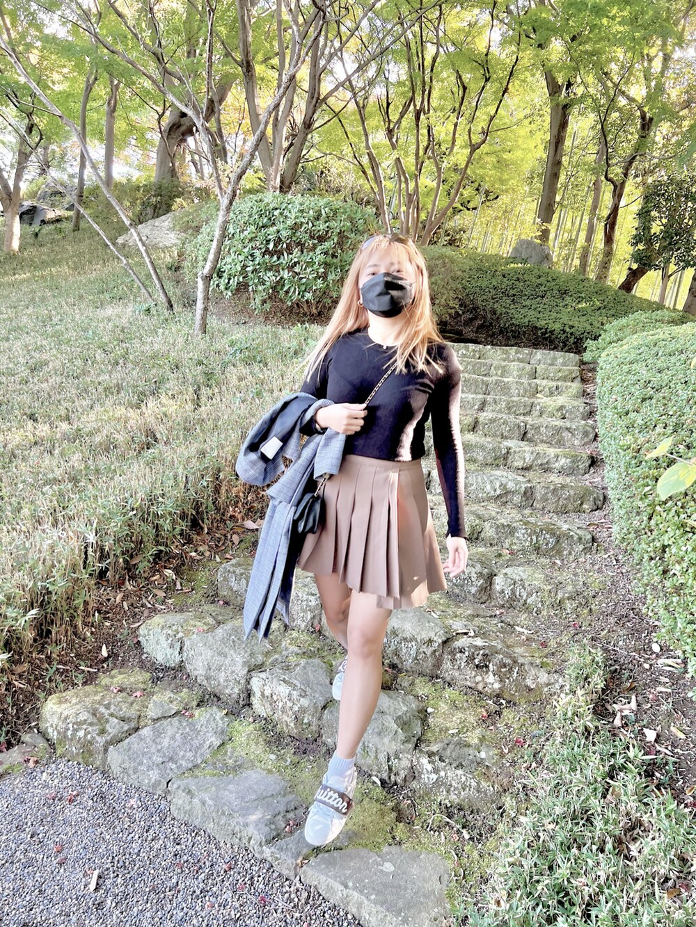 ホワイト系のスニーカー、ブラック系のニット/セーター、ベージュ系のスカートを着用したレディースの夏コーディネートの2枚目の写真