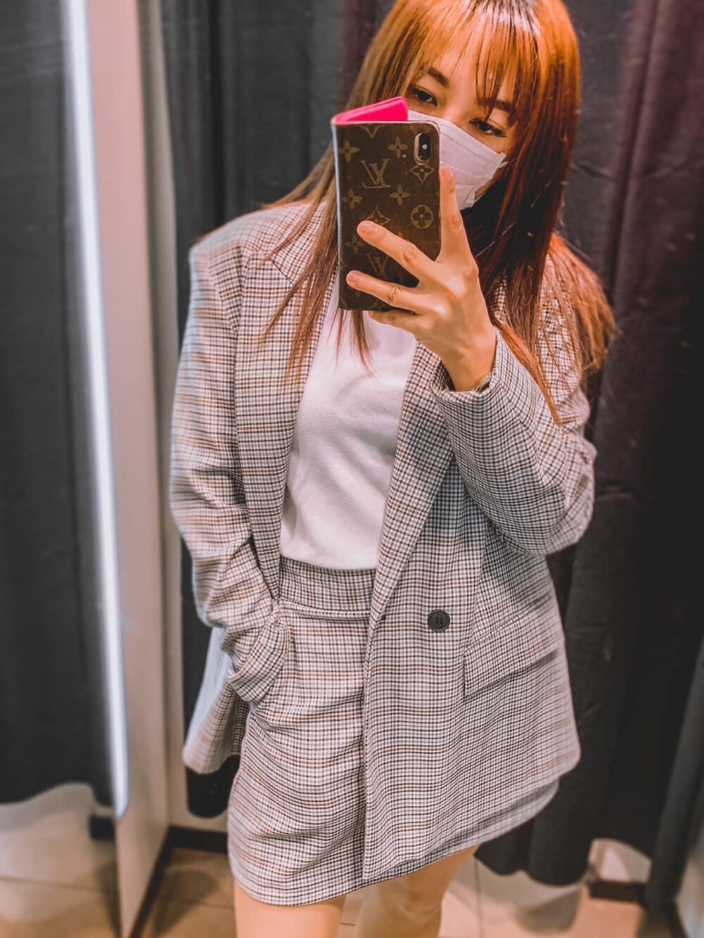 グレー系のテーラードジャケット、グレー系のスカート、ピンク系のスマホケース/カバーを着用したレディースの秋コーディネートの2枚目の写真