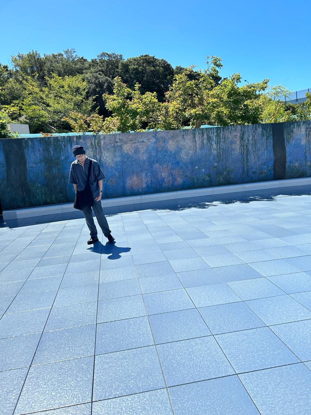 ブルー系のTシャツ/カットソー、グレー系のショルダーバッグ、ブラック系のシューズを着用したメンズの夏コーディネートの5枚目の写真