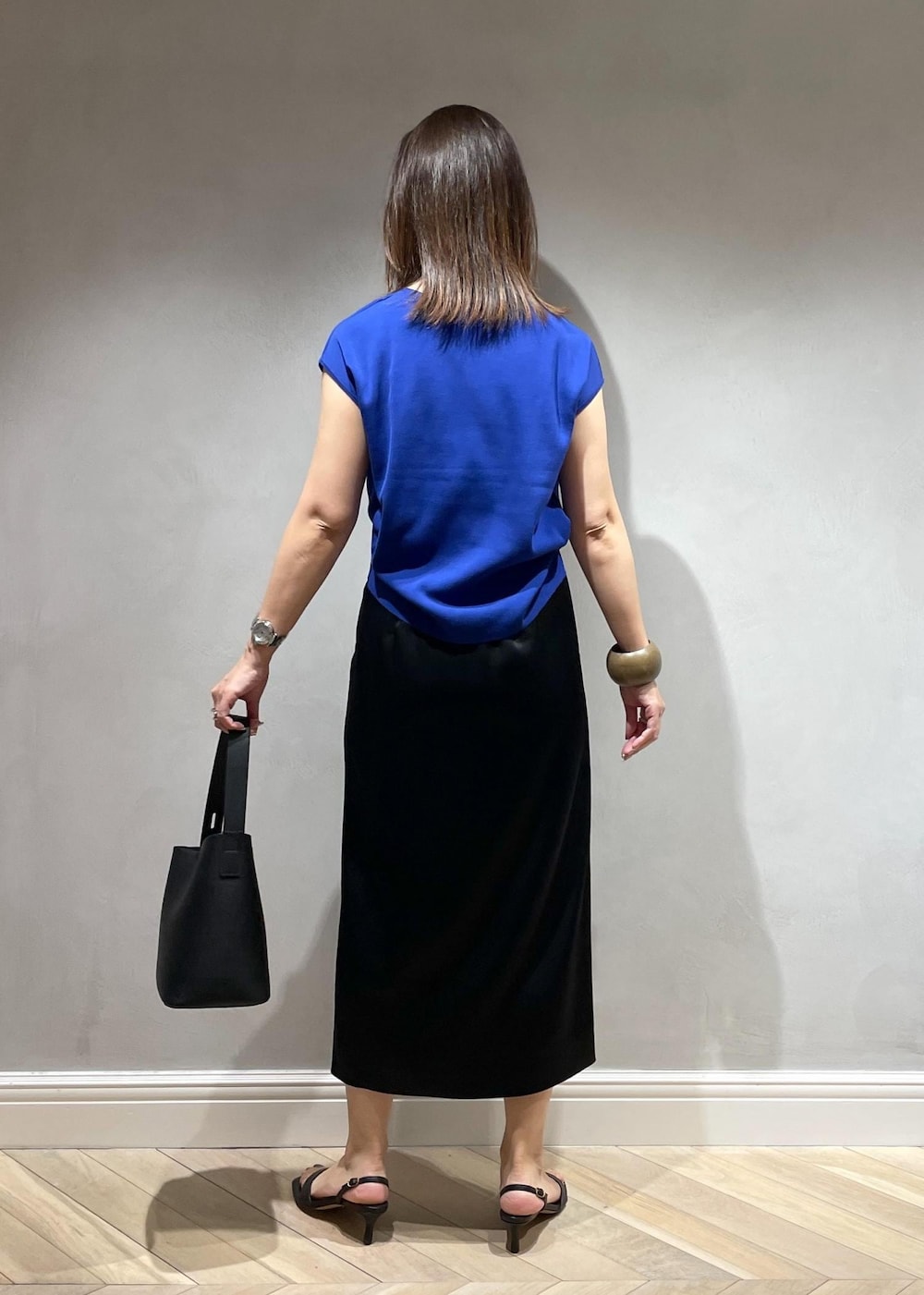 ブラック系のサンダル、ブラック系のハンドバッグ、ブルー系のニット/セーターを着用したレディースの夏コーディネートの4枚目の写真