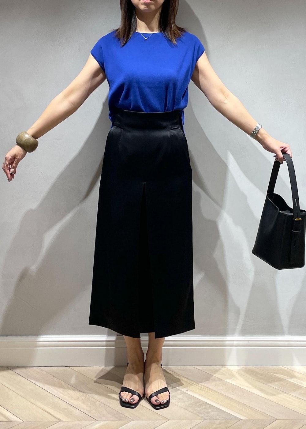 ブラック系のサンダル、ブラック系のハンドバッグ、ブルー系のニット/セーターを着用したレディースの夏コーディネートの5枚目の写真