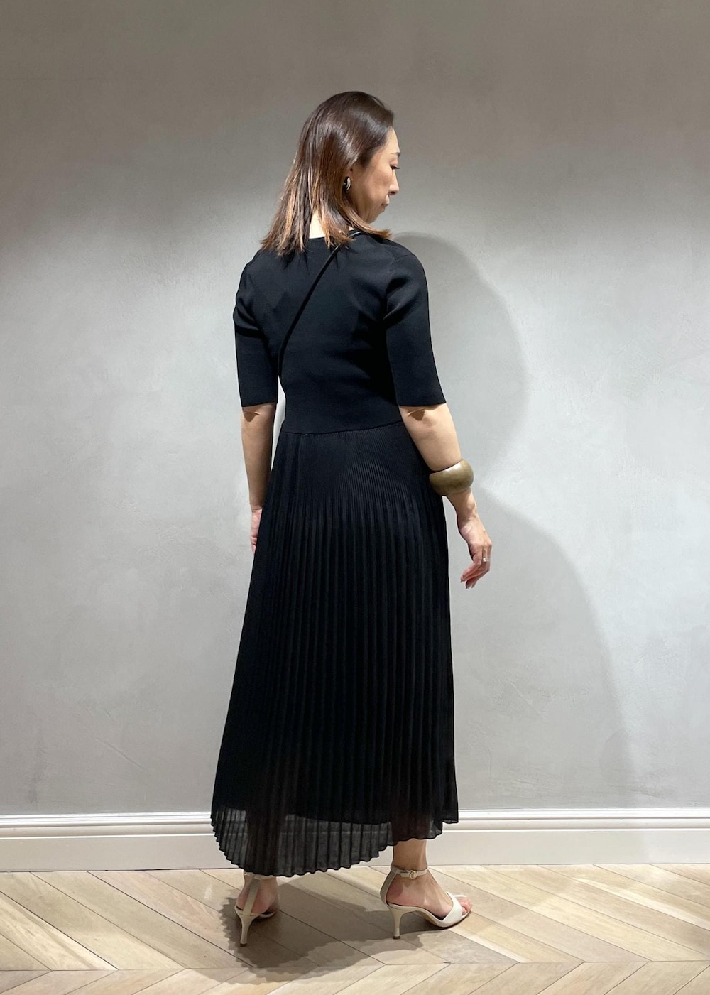 ブラック系のハンドバッグ、ホワイト系のサンダル、ブラック系のワンピースを着用したレディースの春コーディネートの4枚目の写真