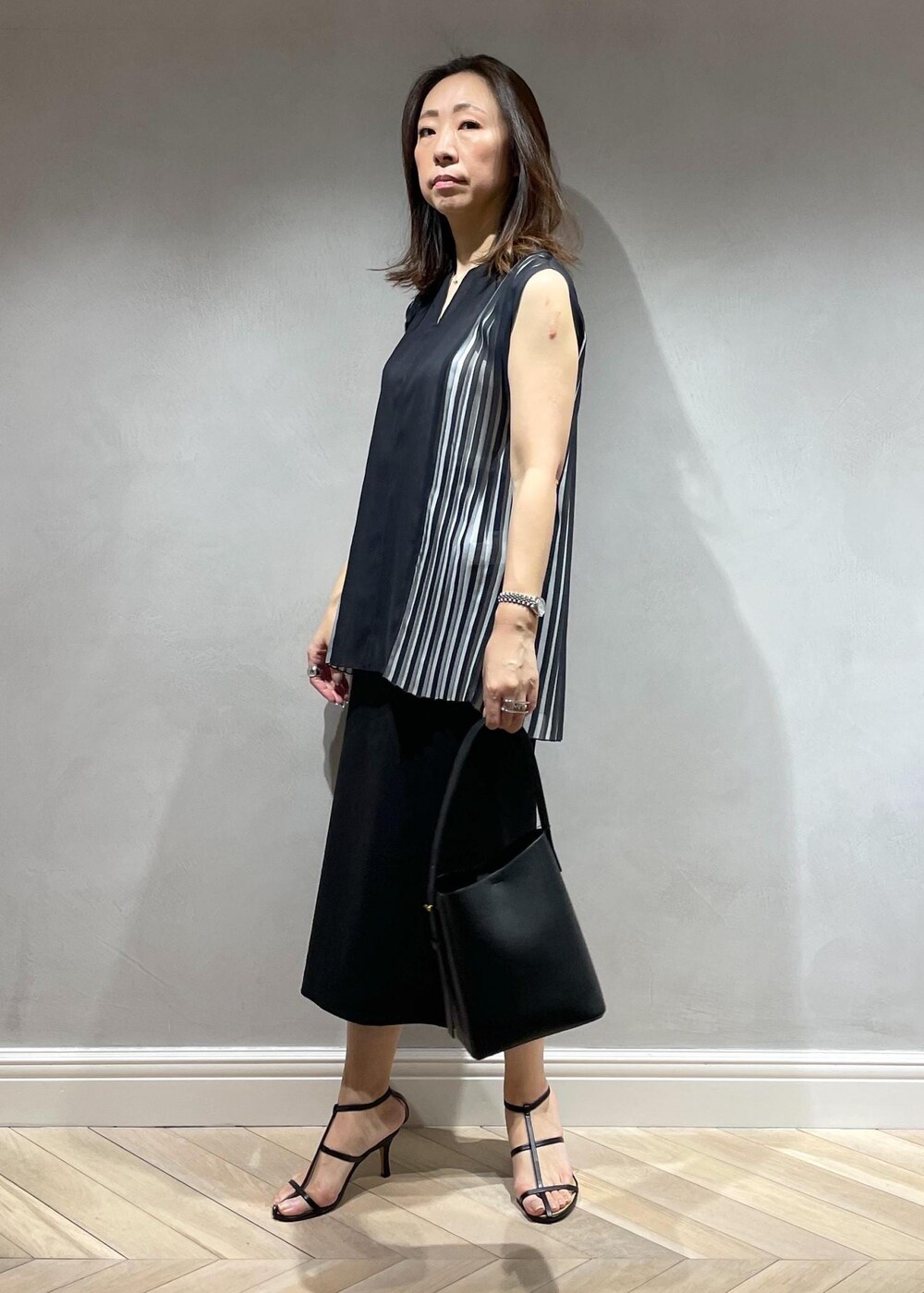 ブラック系のスカート、ブラック系のシャツ/ブラウス、ブラック系のハンドバッグを着用したレディースの春コーディネートの2枚目の写真