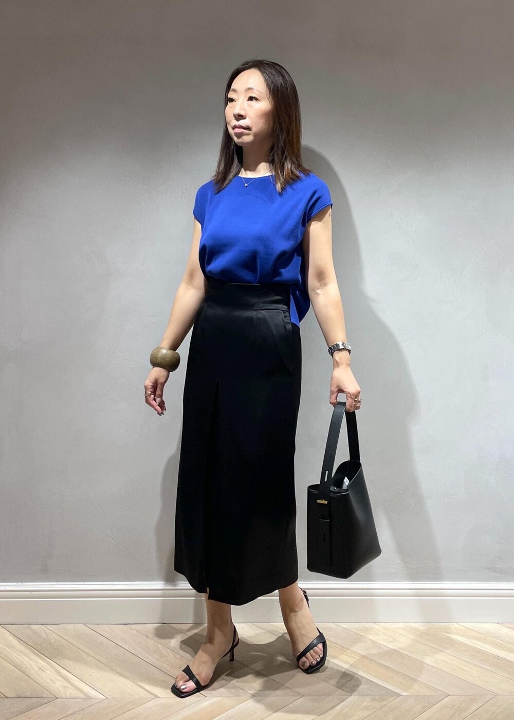 ブラック系のサンダル、ブラック系のハンドバッグ、ブルー系のニット/セーターを着用したレディースの夏コーディネートの2枚目の写真