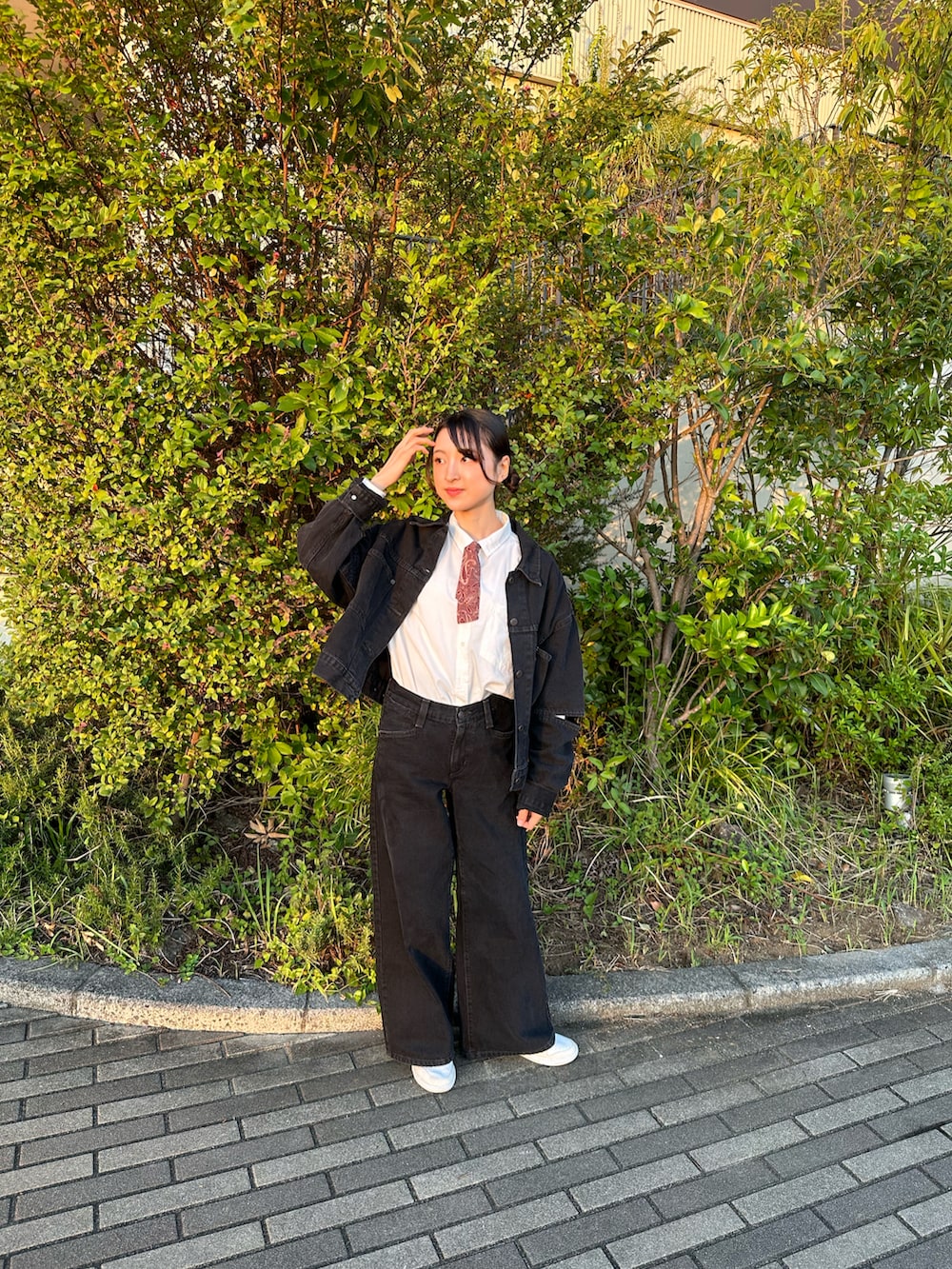 ブラック系のデニムジャケット、ブラック系のデニムパンツ、ホワイト系のスニーカーを着用したレディースの秋コーディネートの3枚目の写真