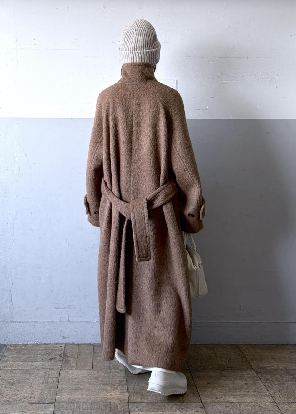 ベージュ系のスニーカー、イエロー系のステンカラーコート、ホワイト系のワンピースを着用したレディースの冬コーディネートの9枚目の写真