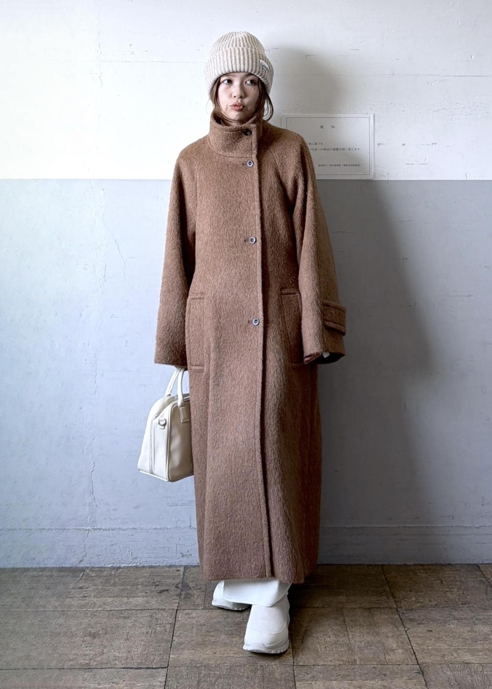 ベージュ系のスニーカー、イエロー系のステンカラーコート、ホワイト系のワンピースを着用したレディースの冬コーディネートの8枚目の写真