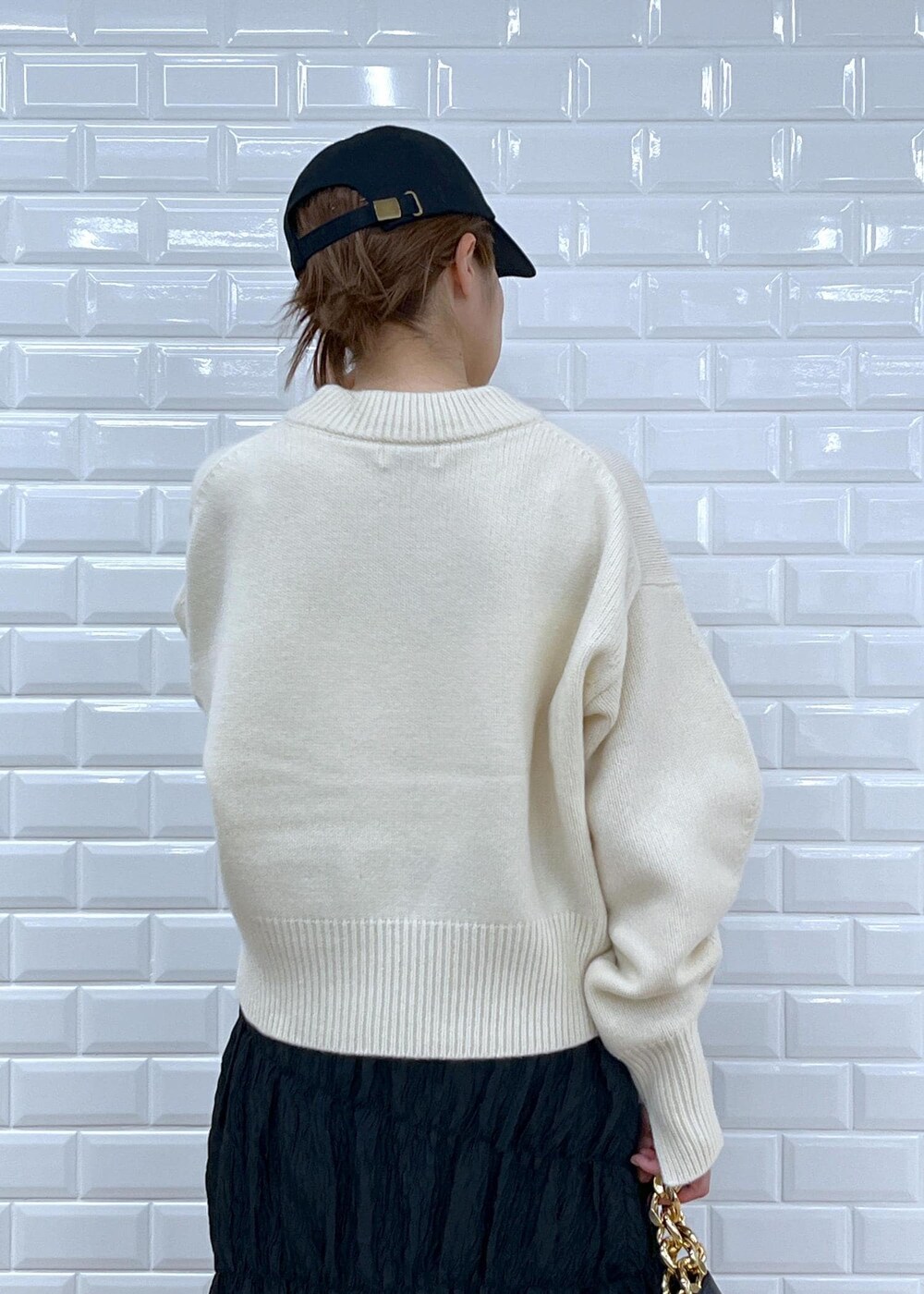 ブラック系のブーツ、ブラック系のスカート、ホワイト系のニット/セーターを着用したレディースの夏コーディネートの6枚目の写真