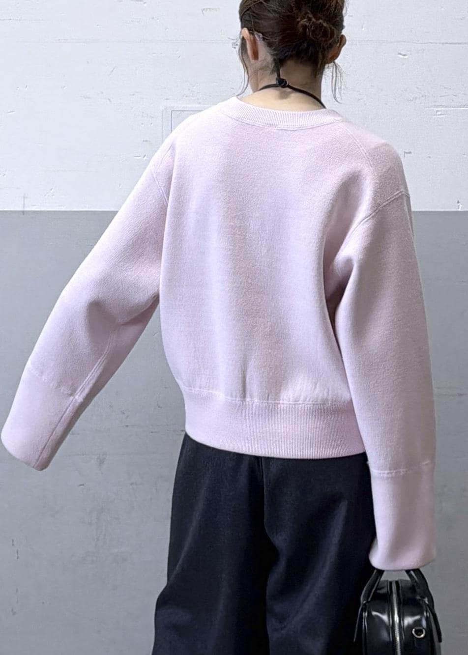 ブラック系のショルダーバッグ、グレー系のスラックス、ピンク系のニット/セーターを着用したレディースの秋コーディネートの7枚目の写真