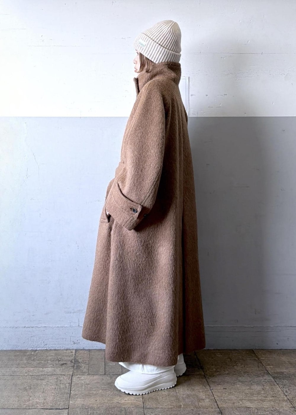 ベージュ系のスニーカー、イエロー系のステンカラーコート、ホワイト系のワンピースを着用したレディースの冬コーディネートの6枚目の写真