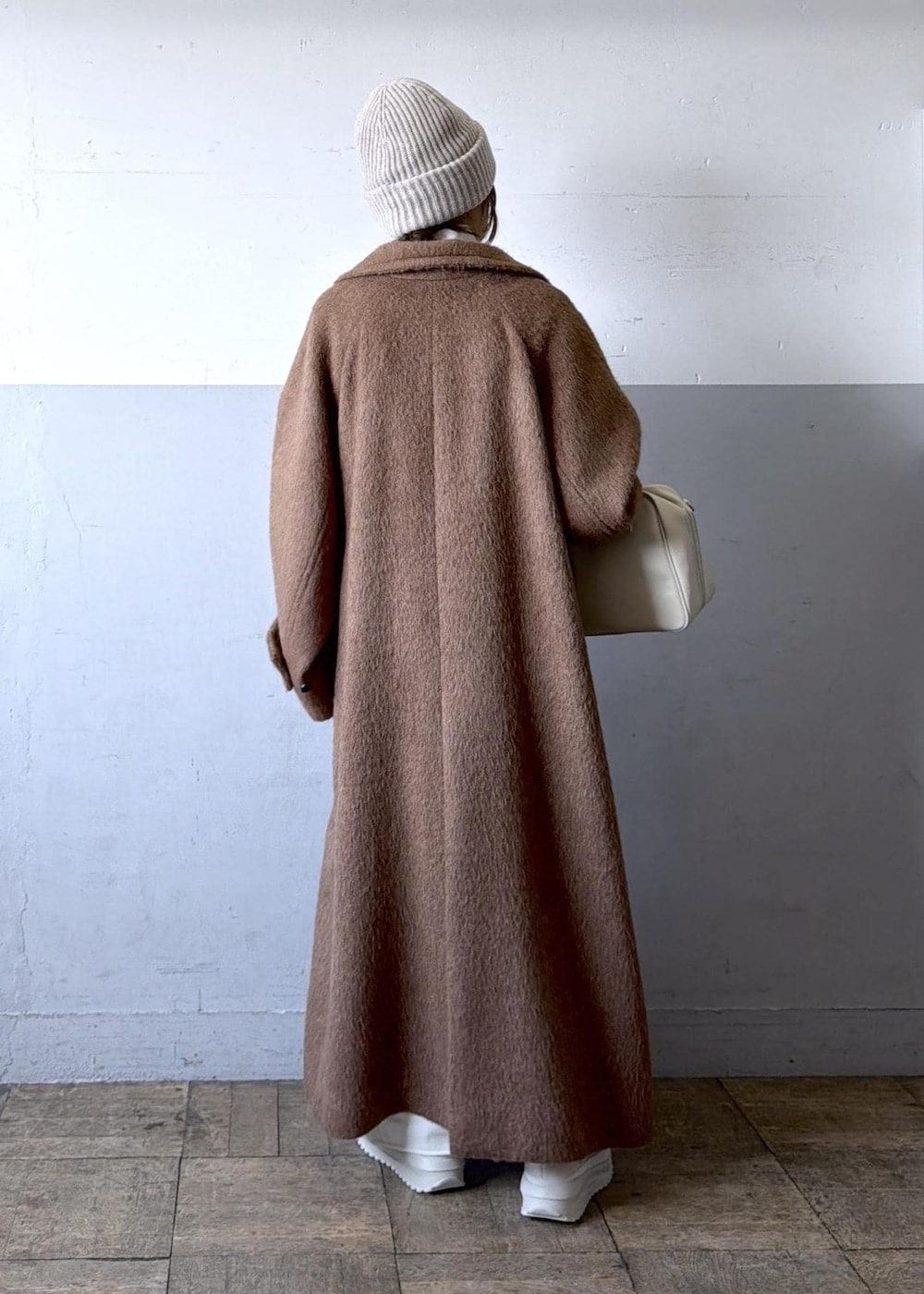 ベージュ系のスニーカー、イエロー系のステンカラーコート、ホワイト系のワンピースを着用したレディースの冬コーディネートの7枚目の写真