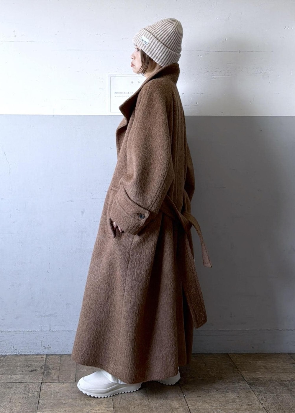 ベージュ系のスニーカー、イエロー系のステンカラーコート、ホワイト系のワンピースを着用したレディースの冬コーディネートの2枚目の写真