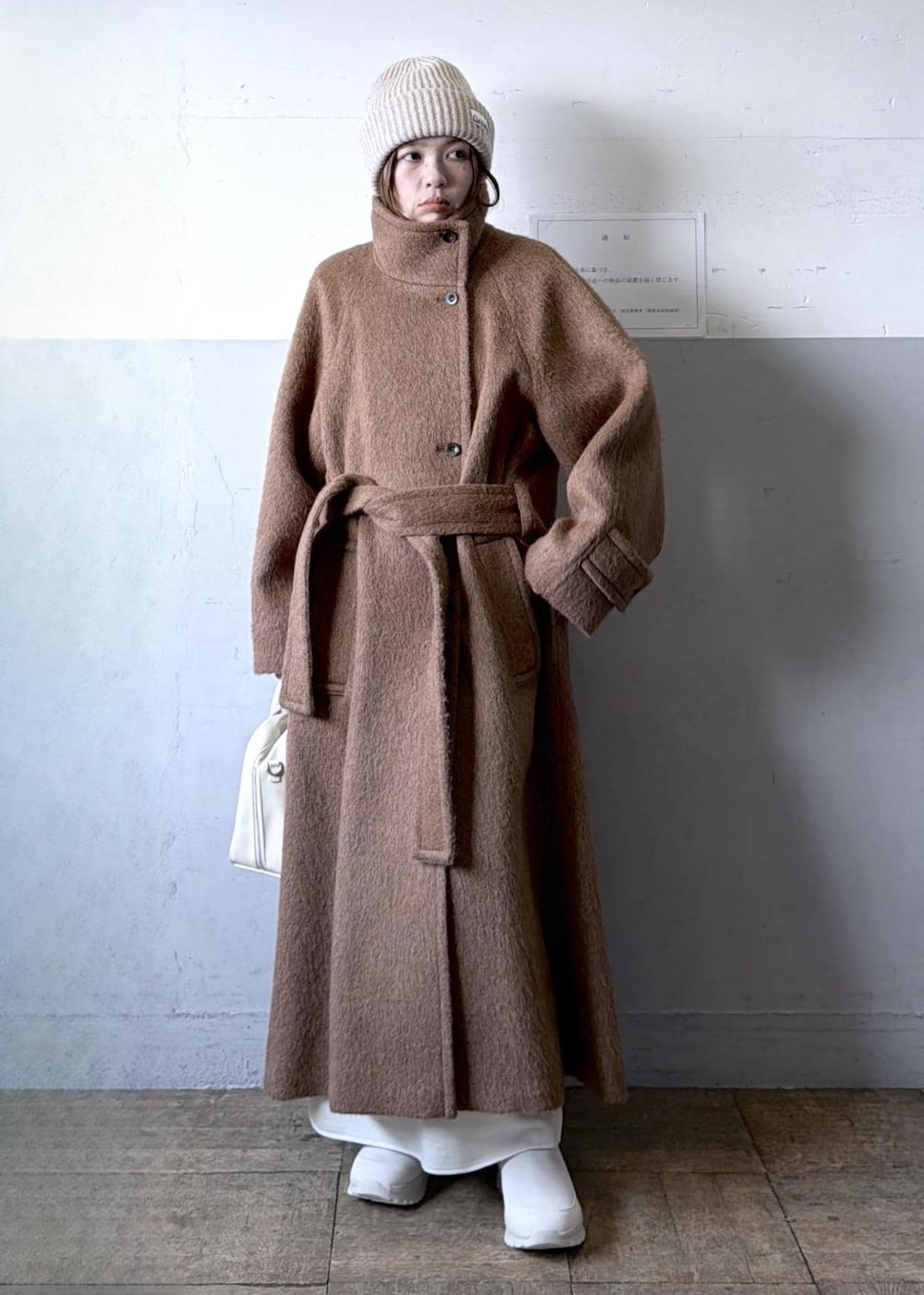 ベージュ系のスニーカー、イエロー系のステンカラーコート、ホワイト系のワンピースを着用したレディースの冬コーディネートの5枚目の写真