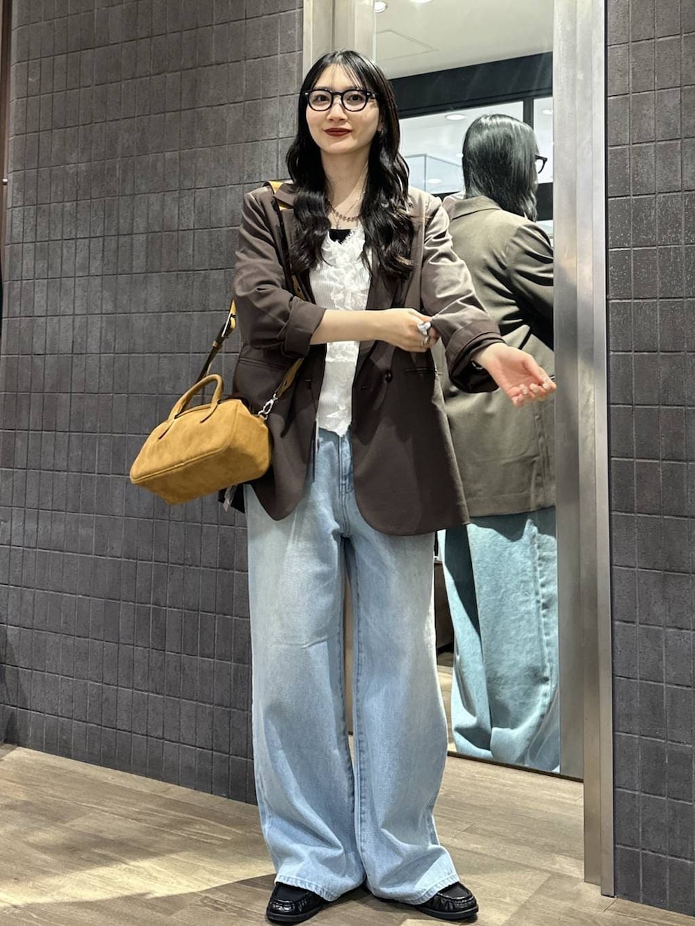 ブラウン系のテーラードジャケット、ブラウン系のボストンバッグ、ブラック系のローファーを着用したレディースの春コーディネートの2枚目の写真