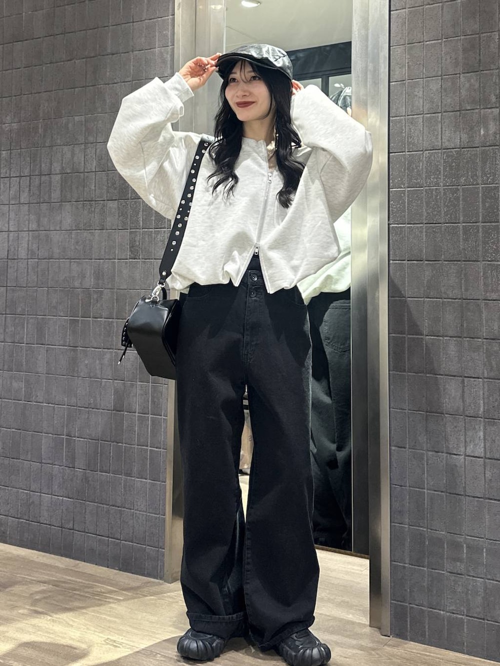 グレー系のスウェット、ブラック系のボストンバッグ、ブラック系のデニムパンツを着用したレディースの冬コーディネートの4枚目の写真