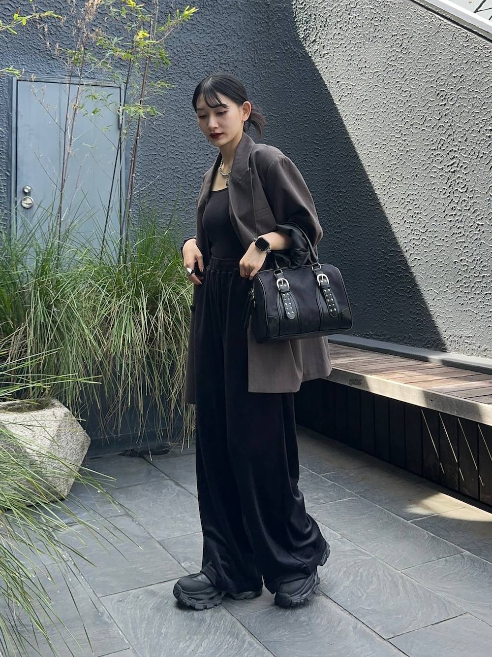 グレー系のテーラードジャケット、ブラック系のブーツ、ブラック系のボストンバッグを着用したレディースの秋コーディネートの2枚目の写真