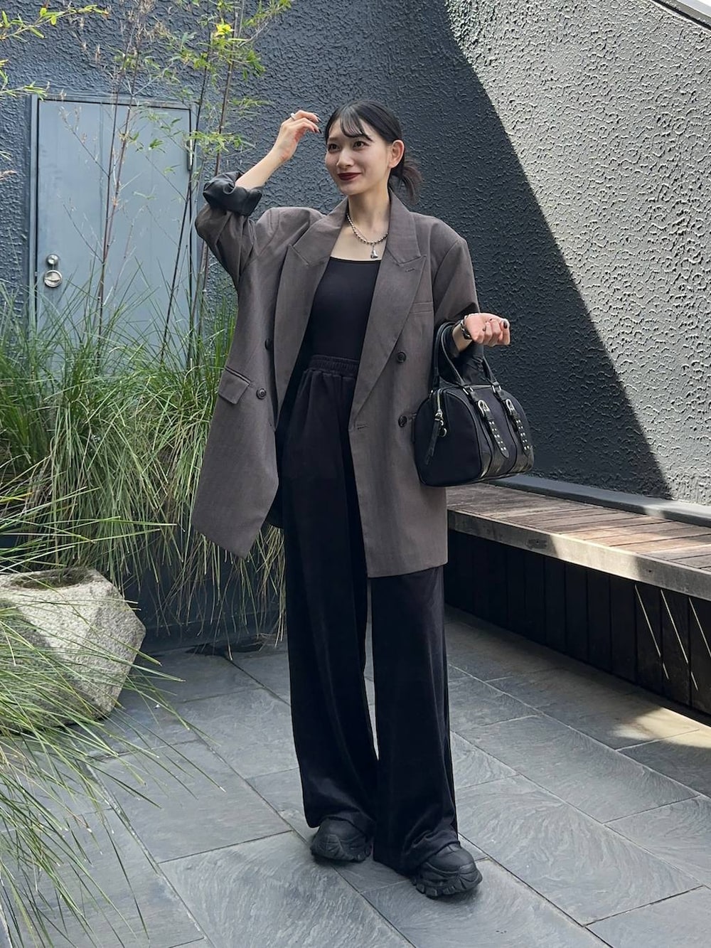 グレー系のテーラードジャケット、ブラック系のブーツ、ブラック系のボストンバッグを着用したレディースの秋コーディネートの3枚目の写真