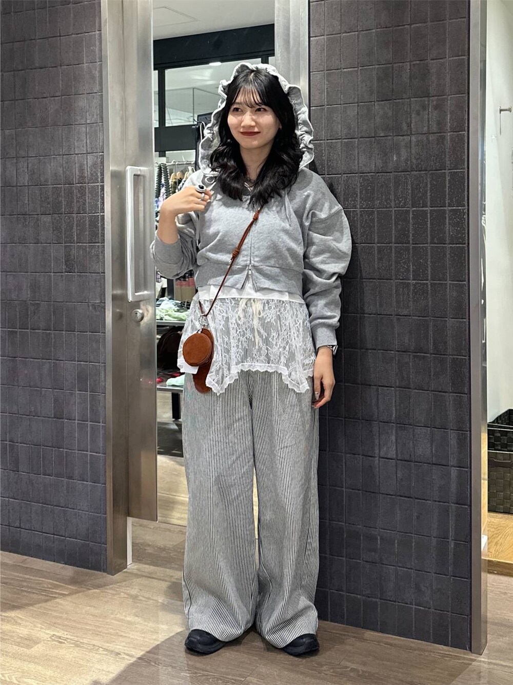 グレー系のパーカー、ホワイト系のキャミソール、ホワイト系のデニムパンツを着用したレディースの秋コーディネートの2枚目の写真