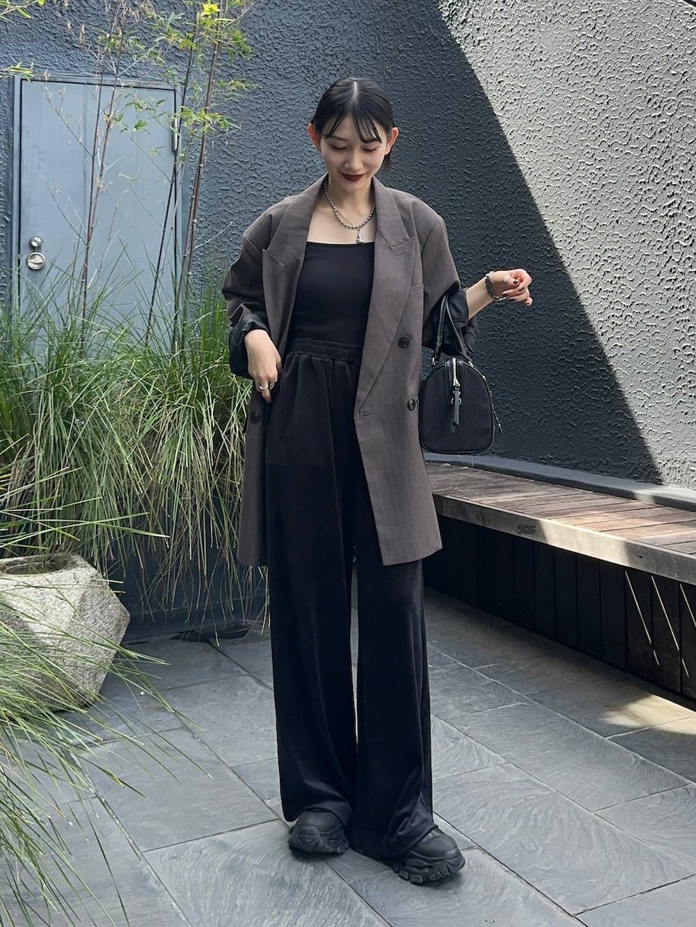 グレー系のテーラードジャケット、ブラック系のブーツ、ブラック系のボストンバッグを着用したレディースの秋コーディネートの4枚目の写真