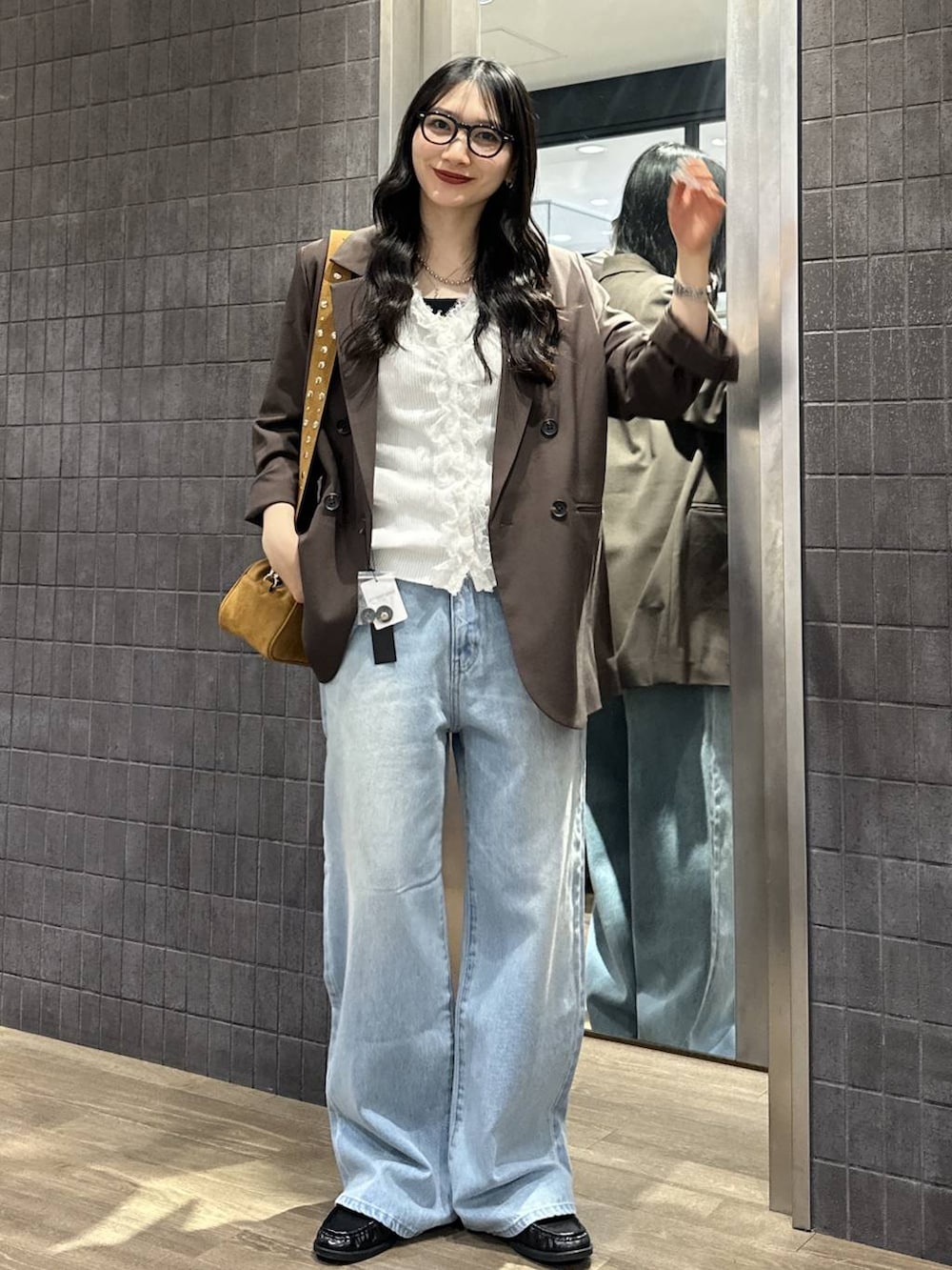 ブラウン系のテーラードジャケット、ブラウン系のボストンバッグ、ブラック系のローファーを着用したレディースの春コーディネートの3枚目の写真