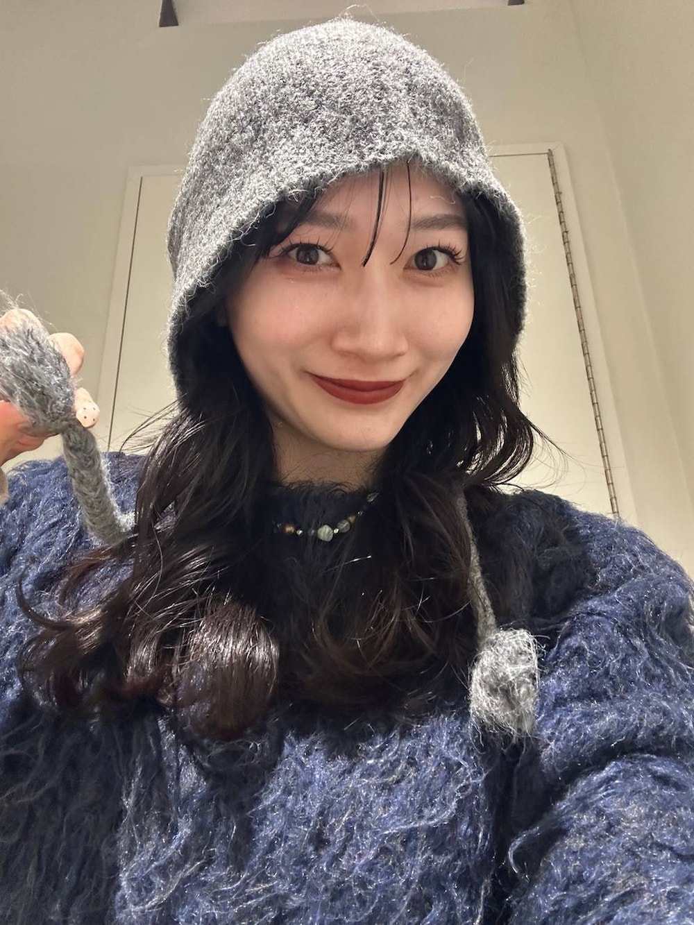 ホワイト系のワンピース、ブルー系のカーディガン/ボレロ、ブラック系のデニムパンツを着用したレディースの冬コーディネートの2枚目の写真