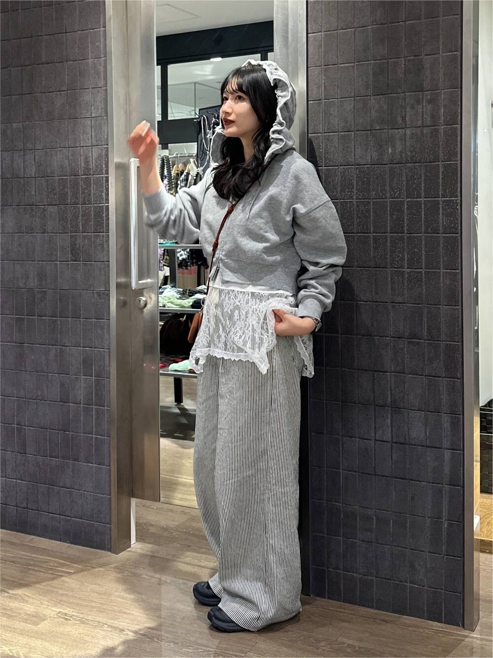 グレー系のパーカー、ホワイト系のキャミソール、ホワイト系のデニムパンツを着用したレディースの秋コーディネートの3枚目の写真