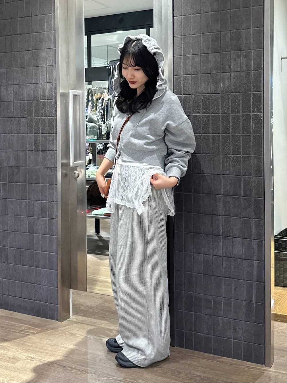 グレー系のパーカー、ホワイト系のキャミソール、ホワイト系のデニムパンツを着用したレディースの秋コーディネートの4枚目の写真