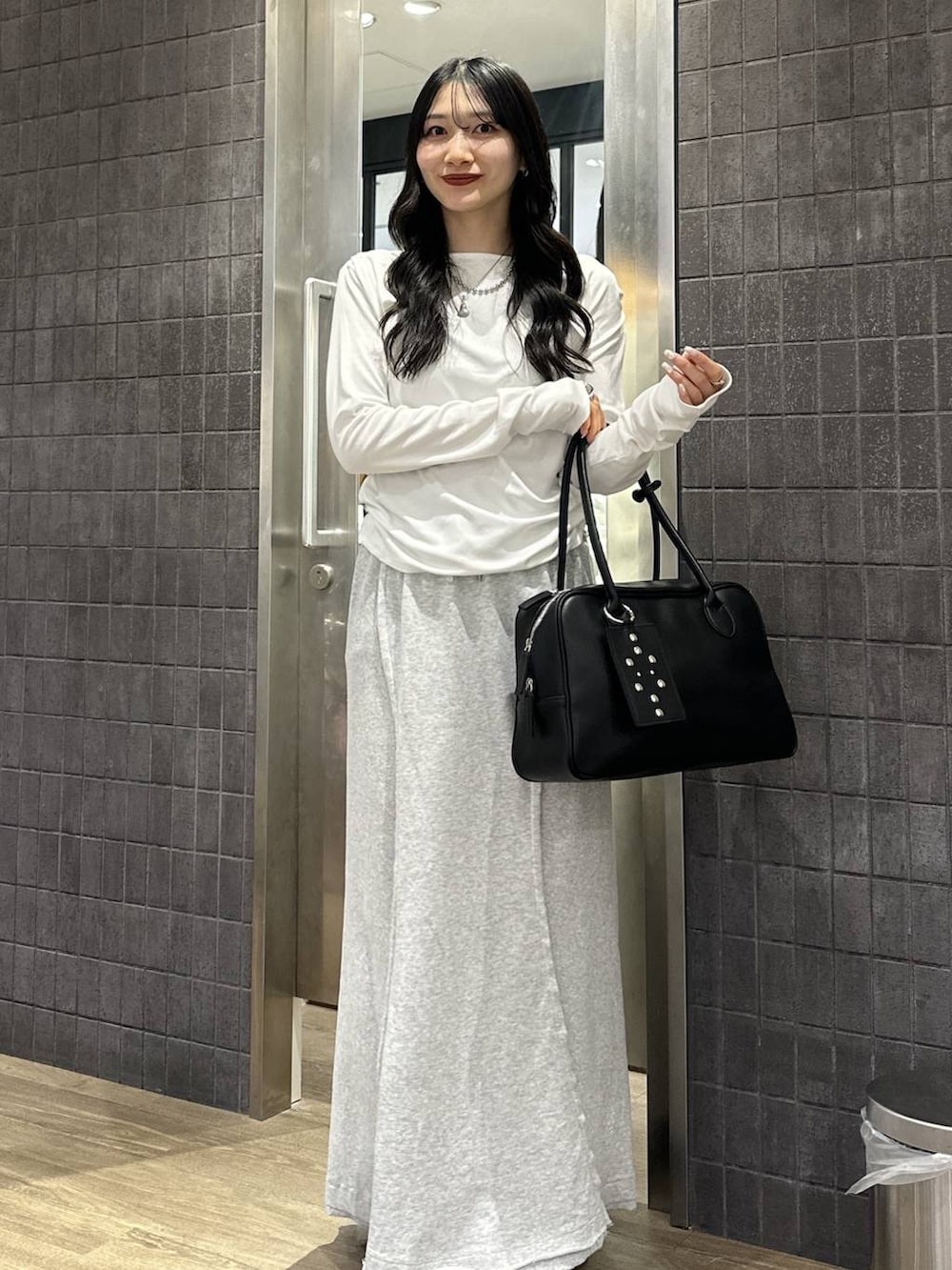 ホワイト系のTシャツ/カットソー、ブラック系のボストンバッグ、グレー系のスカートを着用したレディースの春コーディネートの2枚目の写真