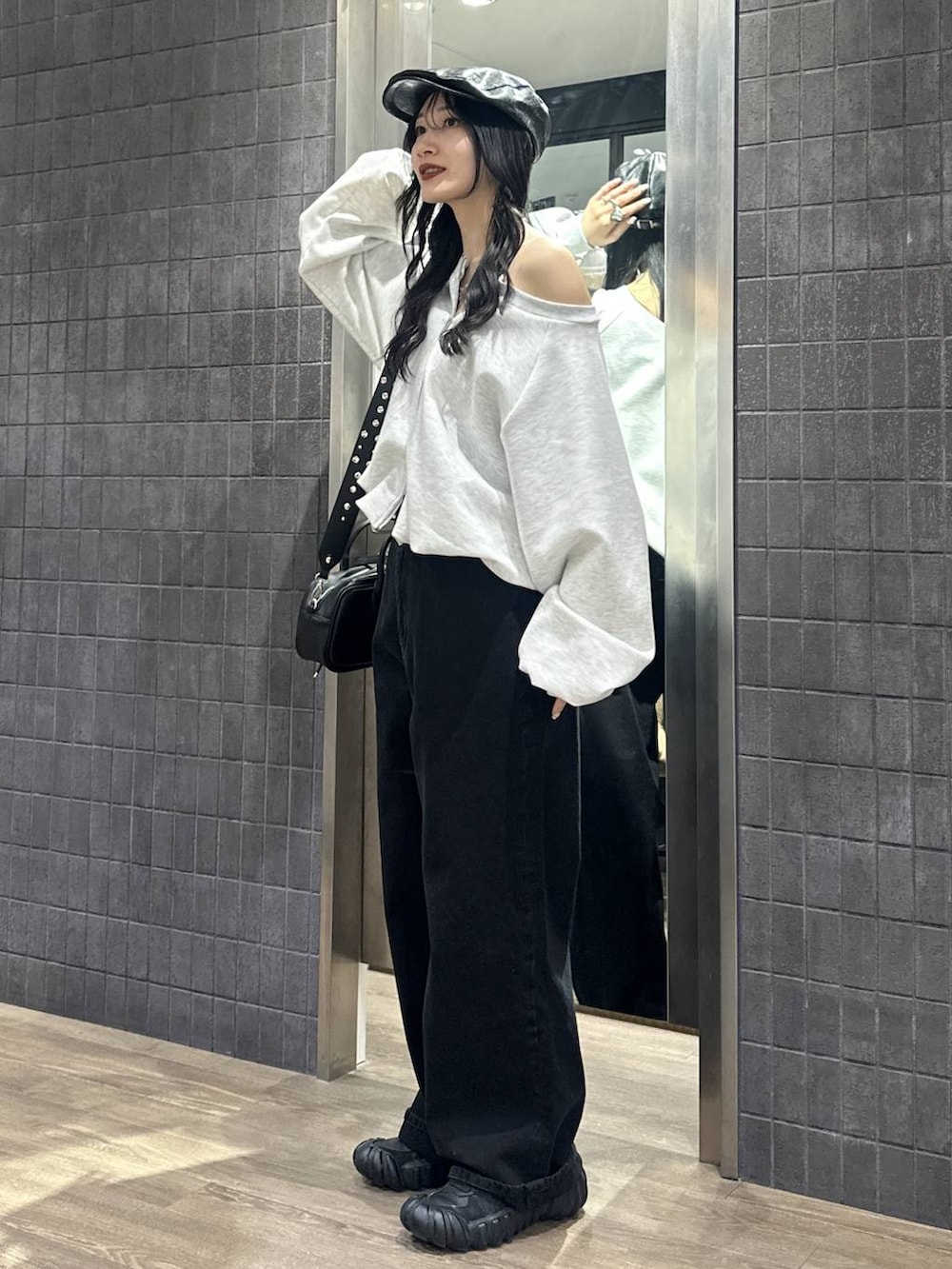 グレー系のスウェット、ブラック系のボストンバッグ、ブラック系のデニムパンツを着用したレディースの冬コーディネートの3枚目の写真