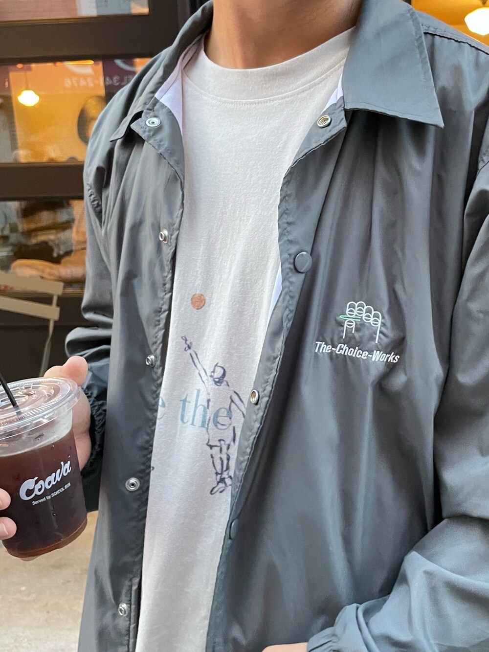 グレー系のTシャツ/カットソー、ブルー系のデニムパンツ、ベージュ系のスニーカーを着用したメンズの秋コーディネートの2枚目の写真