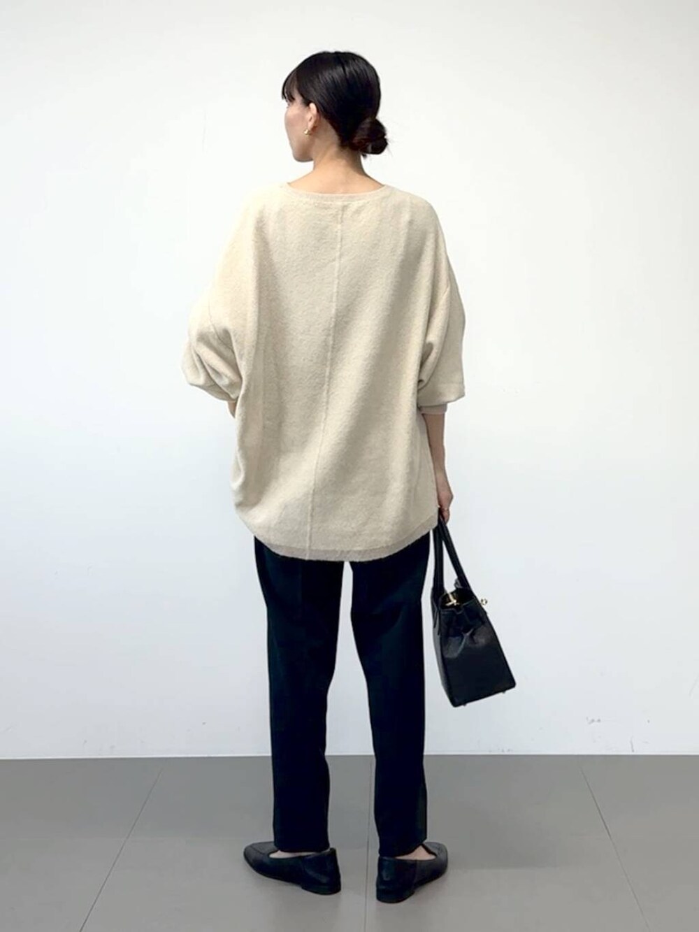 ブラック系のローファー、ブラック系のスラックス、ホワイト系のニット/セーターを着用したレディースの冬コーディネートの2枚目の写真