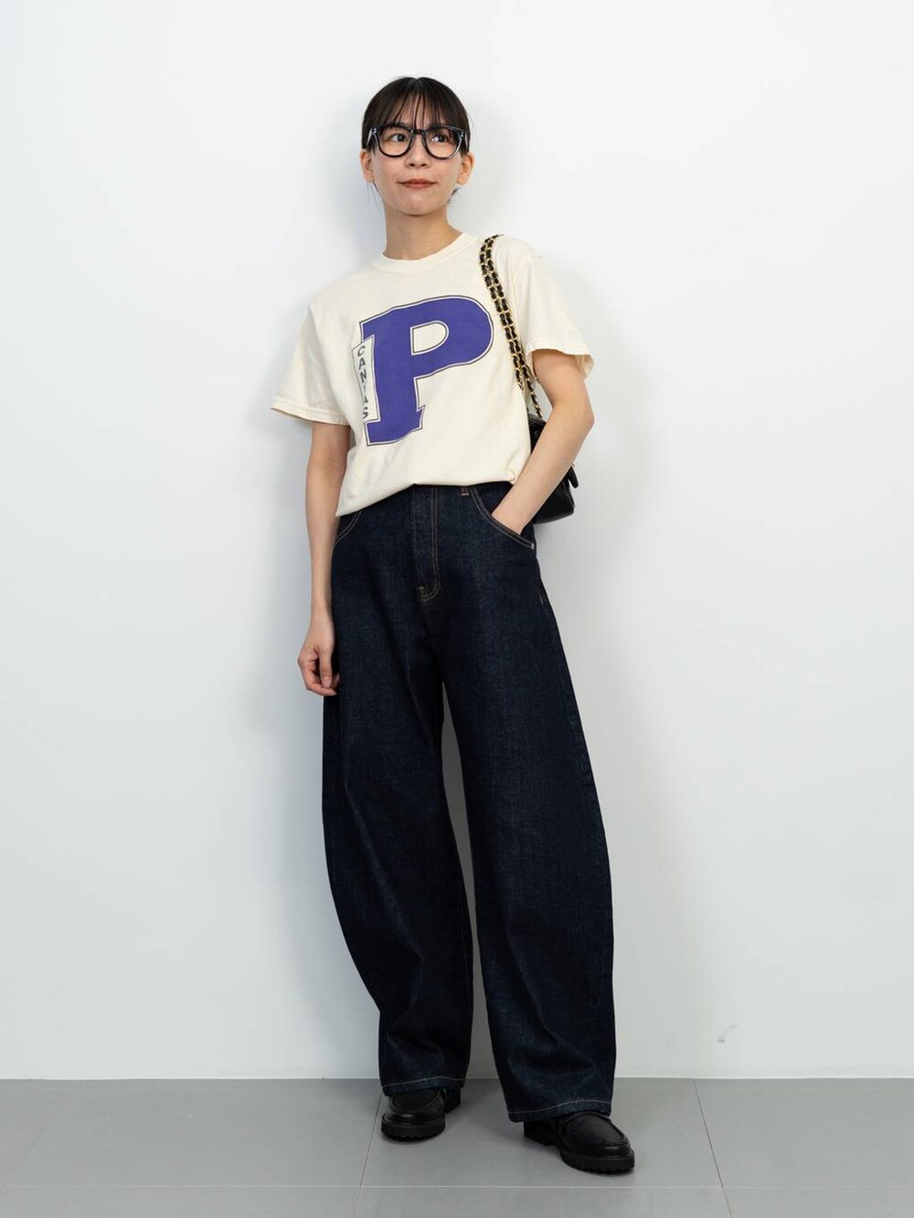 ブラック系のローファー、ブラック系のショルダーバッグ、ブルー系のデニムパンツを着用したレディースの春コーディネートの2枚目の写真