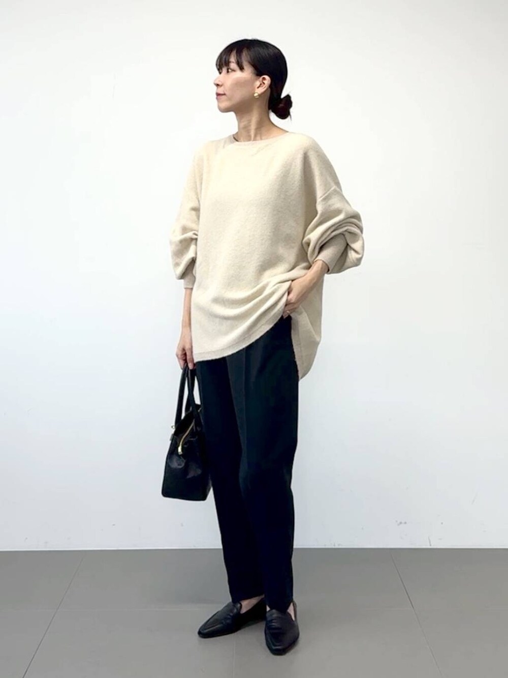 ブラック系のローファー、ブラック系のスラックス、ホワイト系のニット/セーターを着用したレディースの冬コーディネートの4枚目の写真