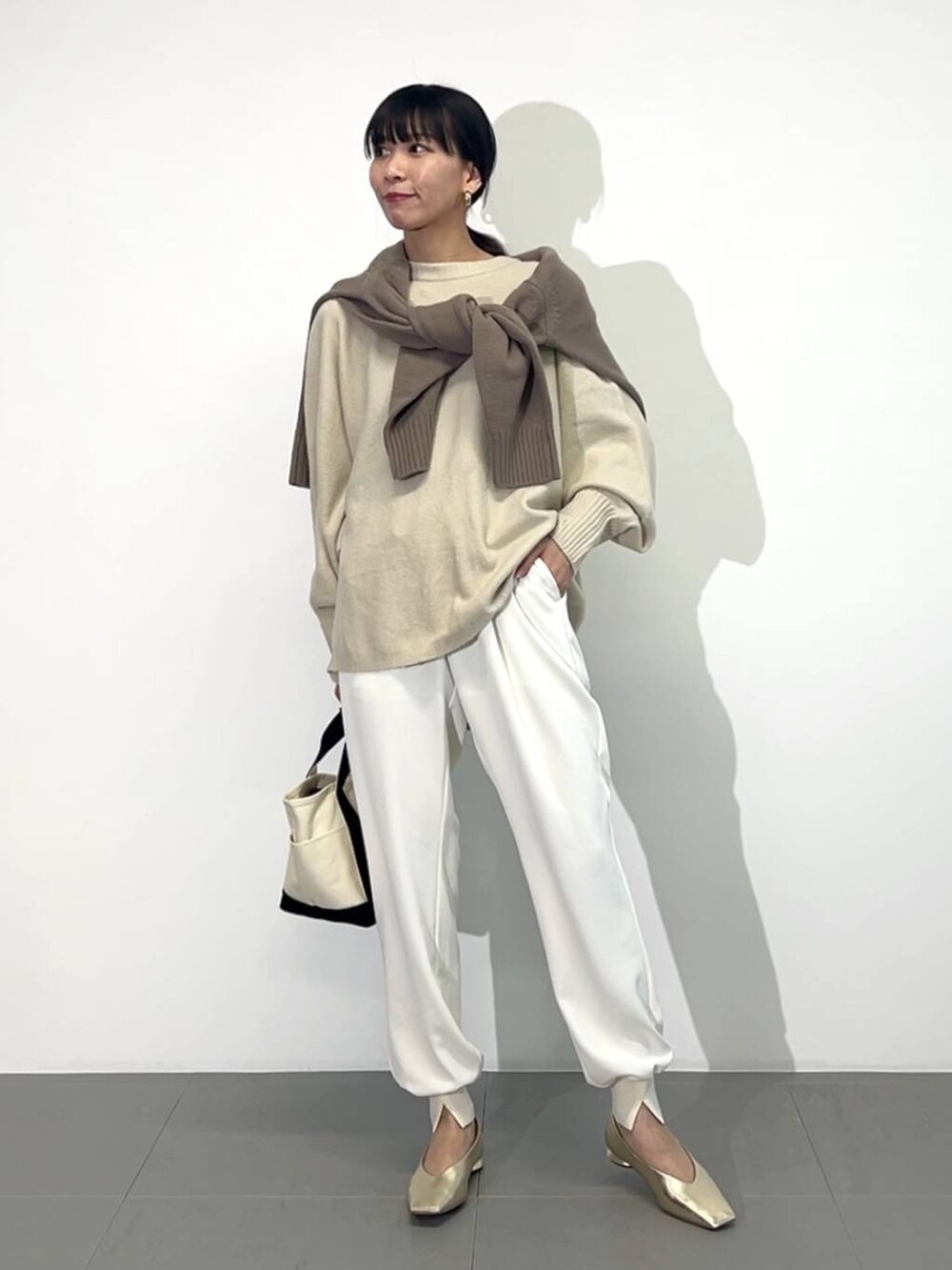 ホワイト系のトートバッグ、ゴールド系のパンプス、ホワイト系のその他パンツを着用したレディースの冬コーディネートの2枚目の写真