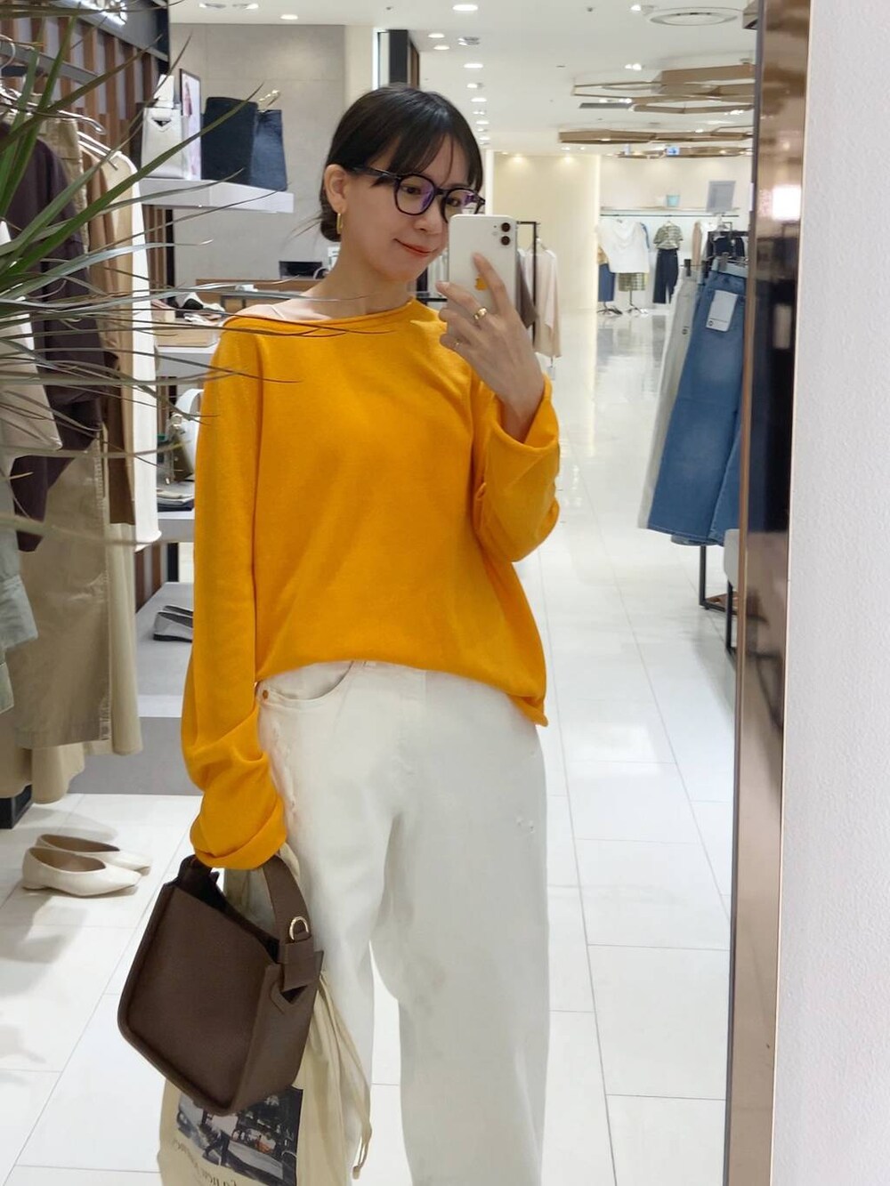 ブラウン系のハンドバッグ、ホワイト系のデニムパンツ、ホワイト系のキャミソールを着用したレディースの春コーディネートの4枚目の写真