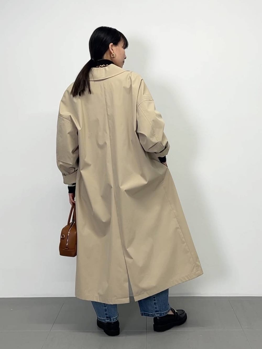 ブラック系のローファー、ブラック系のニット/セーター、ブラウン系のハンドバッグを着用したレディースの冬コーディネートの3枚目の写真