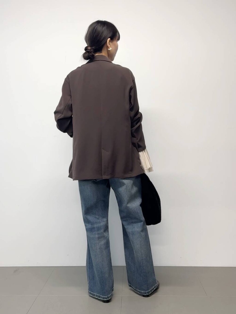 ブラウン系のテーラードジャケット、ブラック系のトートバッグ、その他のチョーカーを着用したレディースの秋コーディネートの2枚目の写真