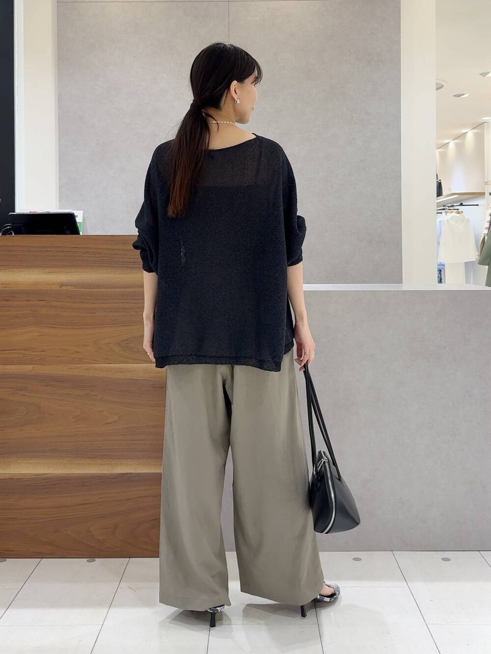 ブラック系のニット/セーター、ブラック系のトートバッグ、ブラック系のキャミソールを着用したレディースの夏コーディネートの4枚目の写真