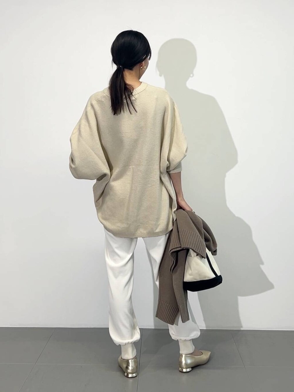 ホワイト系のトートバッグ、ゴールド系のパンプス、ホワイト系のその他パンツを着用したレディースの冬コーディネートの5枚目の写真