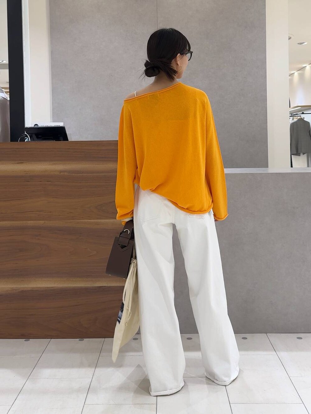 ブラウン系のハンドバッグ、ホワイト系のデニムパンツ、ホワイト系のキャミソールを着用したレディースの春コーディネートの2枚目の写真