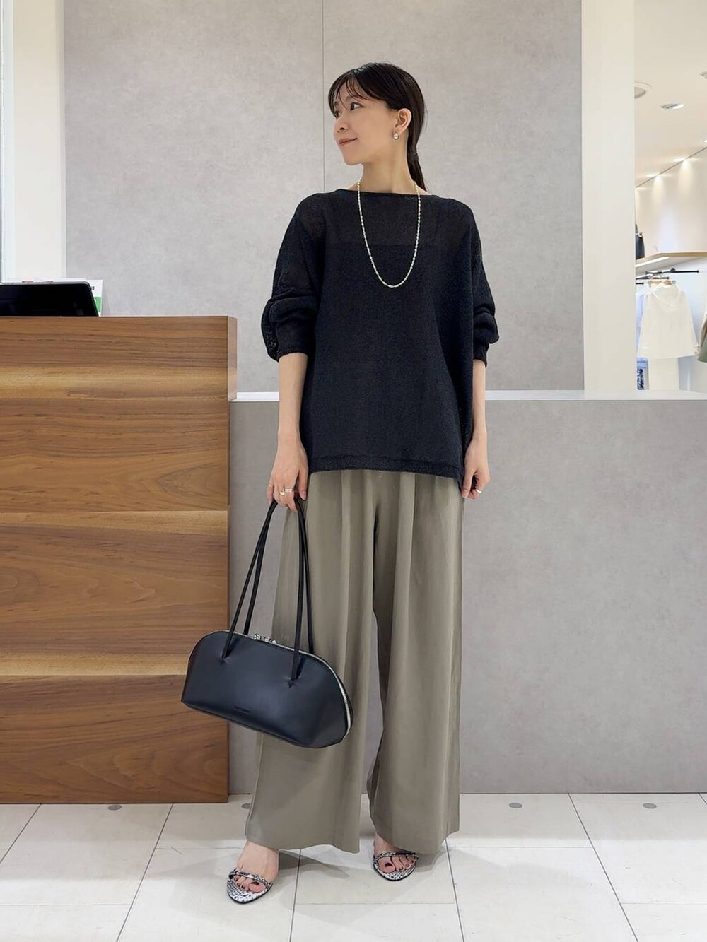 ブラック系のニット/セーター、ブラック系のトートバッグ、ブラック系のキャミソールを着用したレディースの夏コーディネートの2枚目の写真