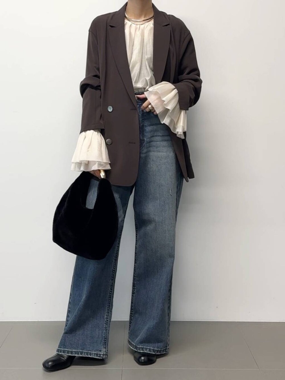 ブラウン系のテーラードジャケット、ブラック系のトートバッグ、その他のチョーカーを着用したレディースの秋コーディネートの4枚目の写真